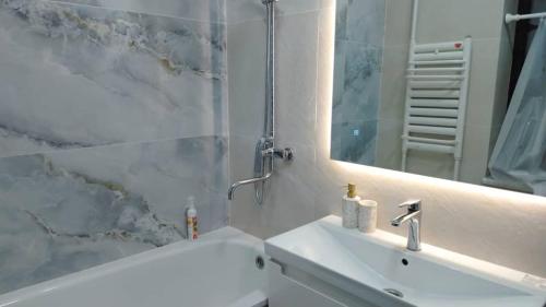 een badkamer met een wastafel, een spiegel en een bad bij Voyage in Karakol