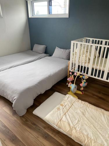 three beds in a room with a crib at shinka 新しいお家ーWestー in Nagano