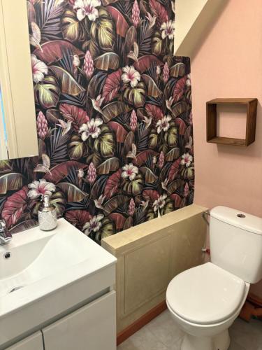 a bathroom with a toilet and a flowery shower curtain at La Parisienne Coquine Love and Plaisir - Love Room in Troyes