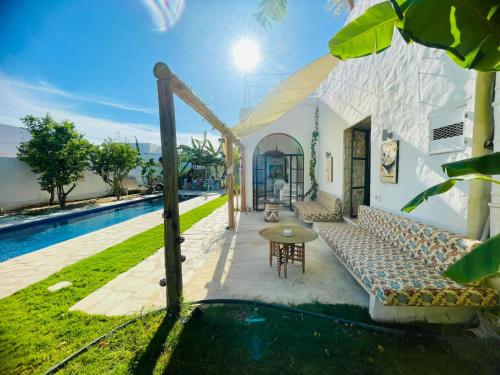 an outdoor patio with a couch and a pool at Casa Dea - Bungalow Isis in Hammamet Sud