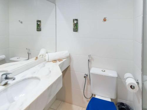 a bathroom with a sink and a toilet and a mirror at Golden Tower Maurilio Biagi by Fênix Hotéis in Ribeirão Preto