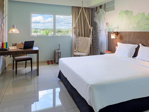 a bedroom with a bed and a desk with a laptop at Golden Tower Maurilio Biagi by Fênix Hotéis in Ribeirão Preto