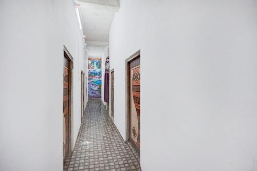 a hallway with tile floors and paintings on the walls at SPOT ON HM HOTEL in Mundarwa