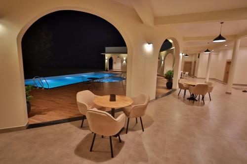 a large room with a swimming pool with tables and chairs at Serene Kabini Wild lodge in Kabini River