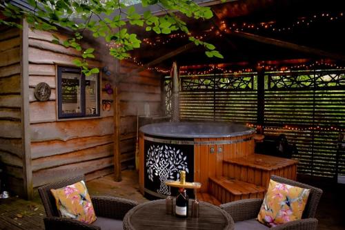 eine Terrasse mit einem Whirlpool, einem Tisch und Stühlen in der Unterkunft Ty Cwtch Cabin - secluded woodland cabin & covered hot tub in Moffat