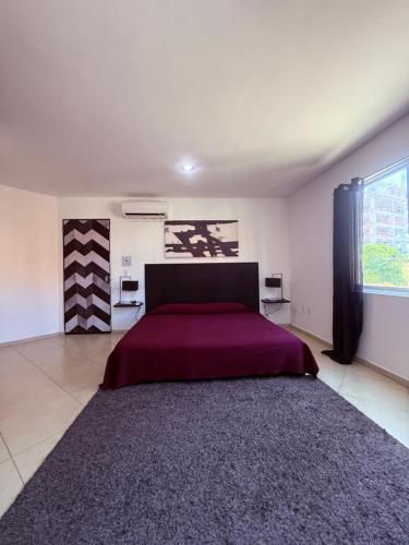 a bedroom with a large bed with a red bedspread at Sabalo's Hausen in Mazatlán