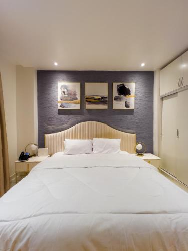 a bedroom with a large white bed with pictures on the wall at Luxury Studio Apt at 233 Boulevard Cantonment-Accra in Accra