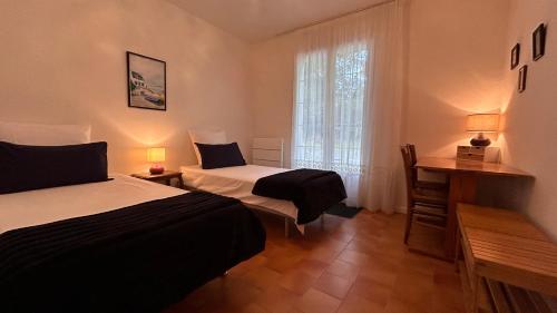een slaapkamer met twee bedden, een bureau en een raam bij Le Clos de l'Autel 