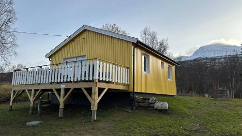 ein großes gelbes Haus mit einer großen Terrasse in der Unterkunft Det gule huset - Nordic Horn in Brostadbotn