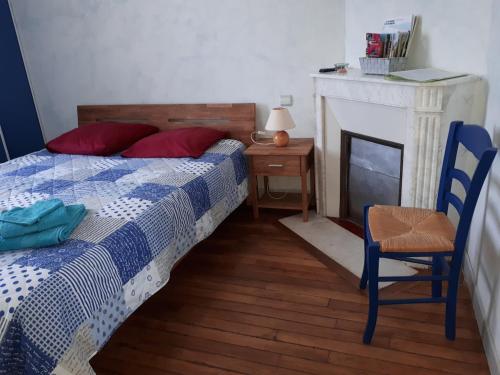 a bedroom with a bed and a chair and a fireplace at Logement indépendant dans cité médiévale in La Charité-sur-Loire