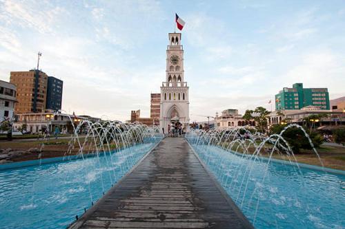 una fontana d'acqua davanti a una torre dell'orologio di departamento con vista al mar con dos habitaciones en iquique a Iquique