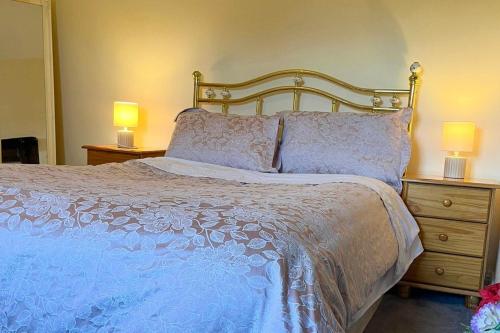 a bedroom with a large bed with two lamps on night stands at 3 Bed Cottage - Sleeps 7 - Parking - Play Area in Carracastle