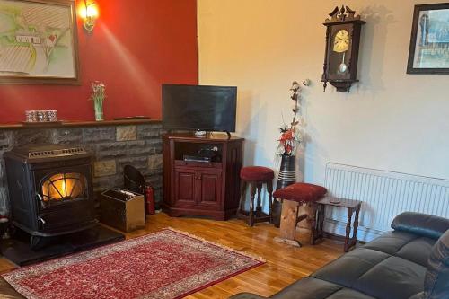 a living room with a couch and a television and a fireplace at 3 Bed Cottage - Sleeps 7 - Parking - Play Area in Carracastle