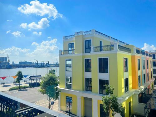 un bâtiment jaune et blanc à côté d'une masse d'eau dans l'établissement Charm Homestay Hải Phòng - Tự Check-in 24h - Gần VinWonders Vũ Yên, à Binh Hai