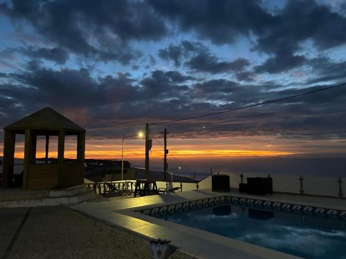 una piscina con cenador y puesta de sol en Mãe Home Foz, en Foz do Arelho
