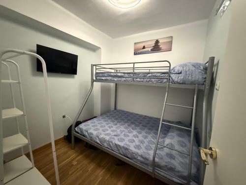 een slaapkamer met 2 stapelbedden en een televisie bij Duplex Ático con terraza y BBQ in Puerto de Sagunto