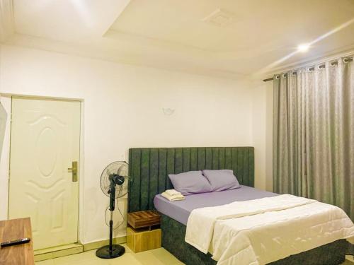 a bedroom with a bed with purple sheets and a fan at GAO-Apartments in Egbelu