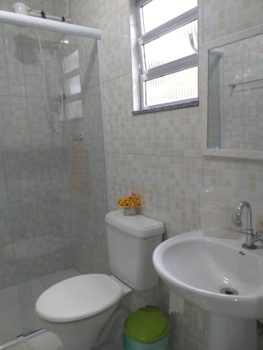 a white bathroom with a toilet and a sink at Kitnet manacá in Paraty