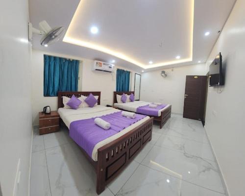 2 bedden in een kamer met paarse lakens en kussens bij Flora inn in Ankola