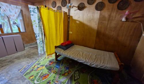 Cette chambre comprend un lit avec un rideau jaune. dans l'établissement J Travel Trail Homestay, à Mahinog