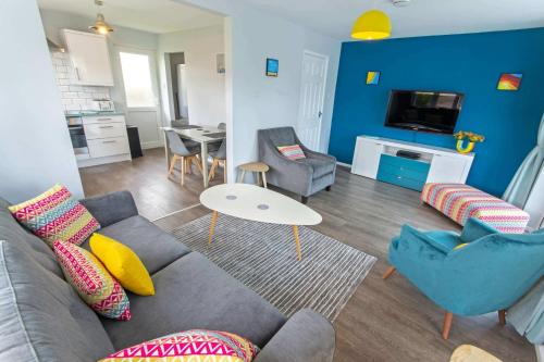 una sala de estar con un sofá y una mesa en Sandbanks Braunton, Stylish Cottage near to Saunton Beach Sleeps 4, en Croyde