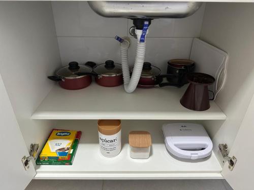 ein Küchenregal mit Töpfen, Pfannen und einer Spüle in der Unterkunft Morada da Fé I 300 m da Canção Nova Cond Da fé in Cachoeira Paulista