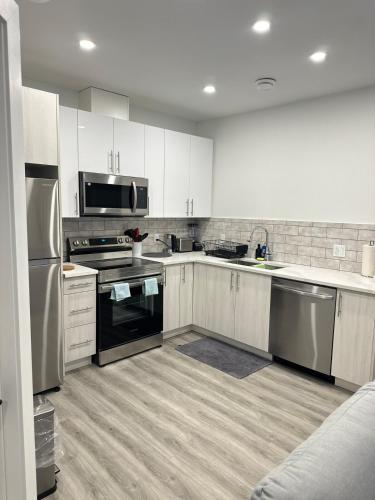 a kitchen with white cabinets and stainless steel appliances at Modern Basement Suite near West Edmonton Mall in Edmonton