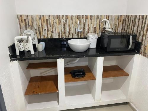 a kitchen counter with a microwave and a sink at Apartamento espaçoso e bem localizado in Boa Vista