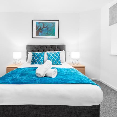 ein Schlafzimmer mit einem großen Bett mit blauer Bettwäsche und blauen Kissen in der Unterkunft Stylish Two Bed Apartment - Speed Wi-Fi - Smart Tv - Parking 201MH in Birmingham