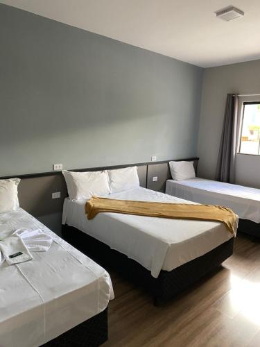 a hotel room with two beds and a window at Hotel Sol Nascente in Assaí