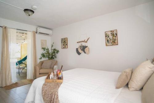 a bedroom with a white bed and a chair at Casa Loba Suite 1 with an outdoor tub in Rincon
