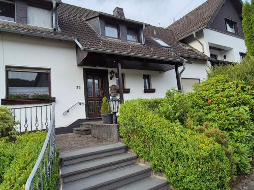 a white house with stairs leading to the front door at Fewo EifelLenz in Hellenthal