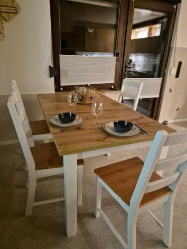 a wooden table with two plates and wine glasses on it at Fewo EifelLenz in Hellenthal