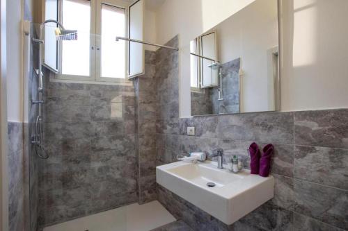a bathroom with a sink and a shower and a mirror at Eva Luxury Saint Remy in Cagliari