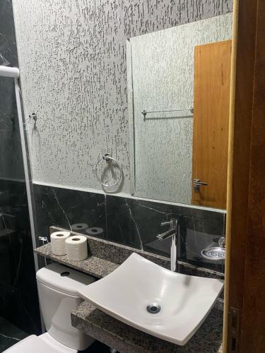 a bathroom with a white sink and a mirror at Hotel Sol Nascente in Assaí