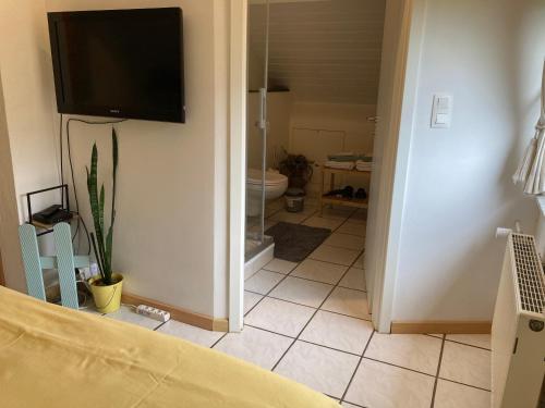 a bedroom with a tv on the wall and a bathroom at B&B Haus Jola in Nidrum