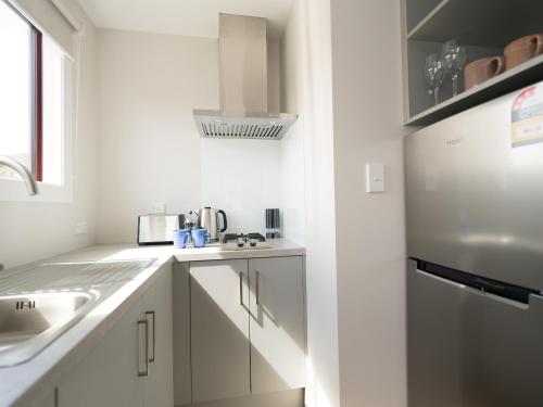 Una cocina blanca con fregadero y refrigerador. en Dawsons Hotel, en Reefton