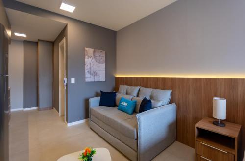 a living room with a couch with blue pillows at Upper West Perdizes by Xtay - Nubank Parque a 500m - antigo Allianz Parque - estúdio moderno com cozinha e vista da cidade in São Paulo