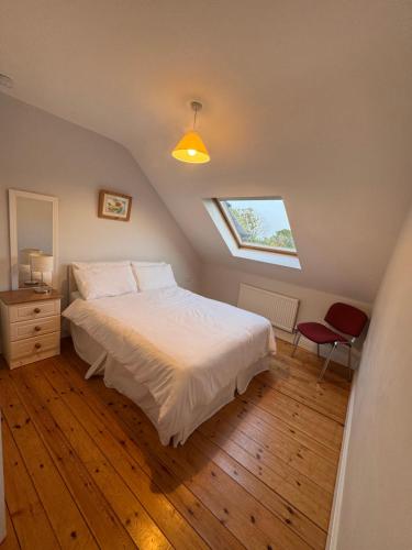 a bedroom with a white bed and a window at Modern Home in the Heart of Rosscarbery Village in Rosscarbery