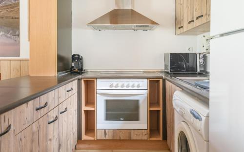 a kitchen with wooden cabinets and a stove top oven at Casa Los Altos de Santiago in Villanúa