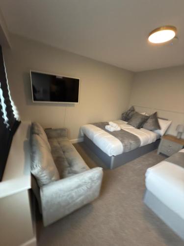 a room with two beds and a couch and a flat screen tv at Modern Studio London Near Hospital in Thornton Heath