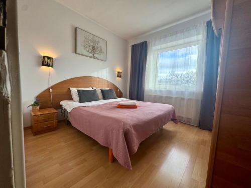 a bedroom with a bed with a pink blanket and a window at Tatari Residence by Rikas Hotels in Tallinn