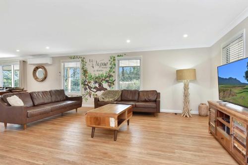 a living room with couches and a flat screen tv at Rose at the Vineyard in Pokolbin