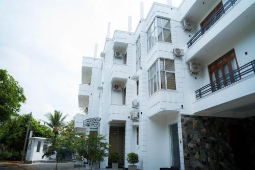 a white building with trees in front of it at Kings Town Hotel Anuradhapura in Nikawatawana