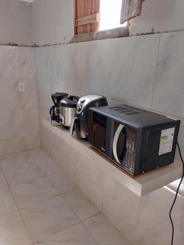 a microwave sitting on a shelf in a kitchen at Pousada degamix in Barroquinha