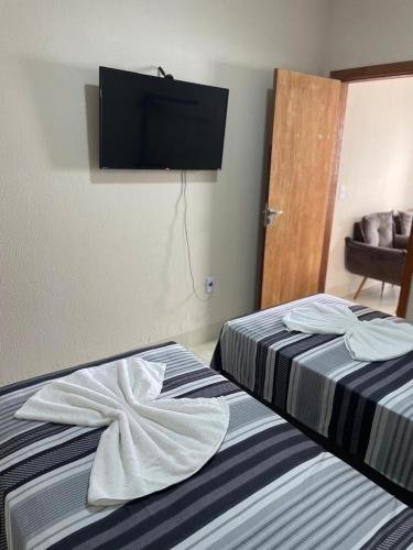 two beds in a room with a television on the wall at Apartamento solteiro sinop 9 in Sinop