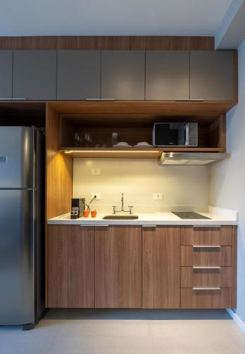 a kitchen with wooden cabinets and a stainless steel refrigerator at Upper West Perdizes by Xtay - Nubank Parque a 500m - antigo Allianz Parque - estúdio moderno com cozinha e vista da cidade in São Paulo