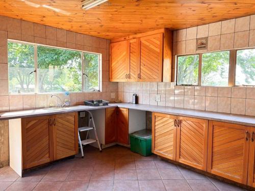 a kitchen with wooden cabinets and a sink and two windows at Field's End in Howick