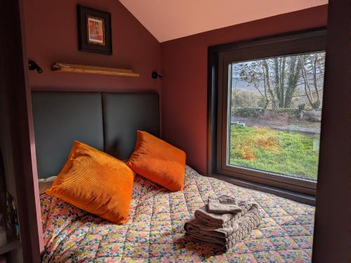 a bedroom with a bed with orange pillows and a window at Tranquil Off-Grid Cabin in Ballina