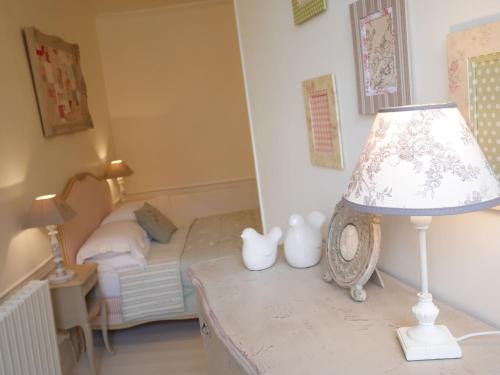 a lamp on a table in a bedroom with a bed at L'Arbre D'Ange in Montmorillon